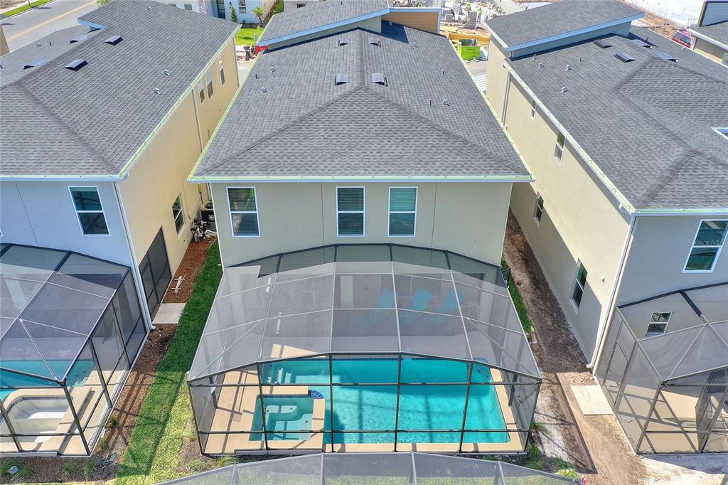 An aerial view shows a two-story house with a screened-in pool and spa — 4285 PROLOGUE WAY, KISSIMMEE, FL