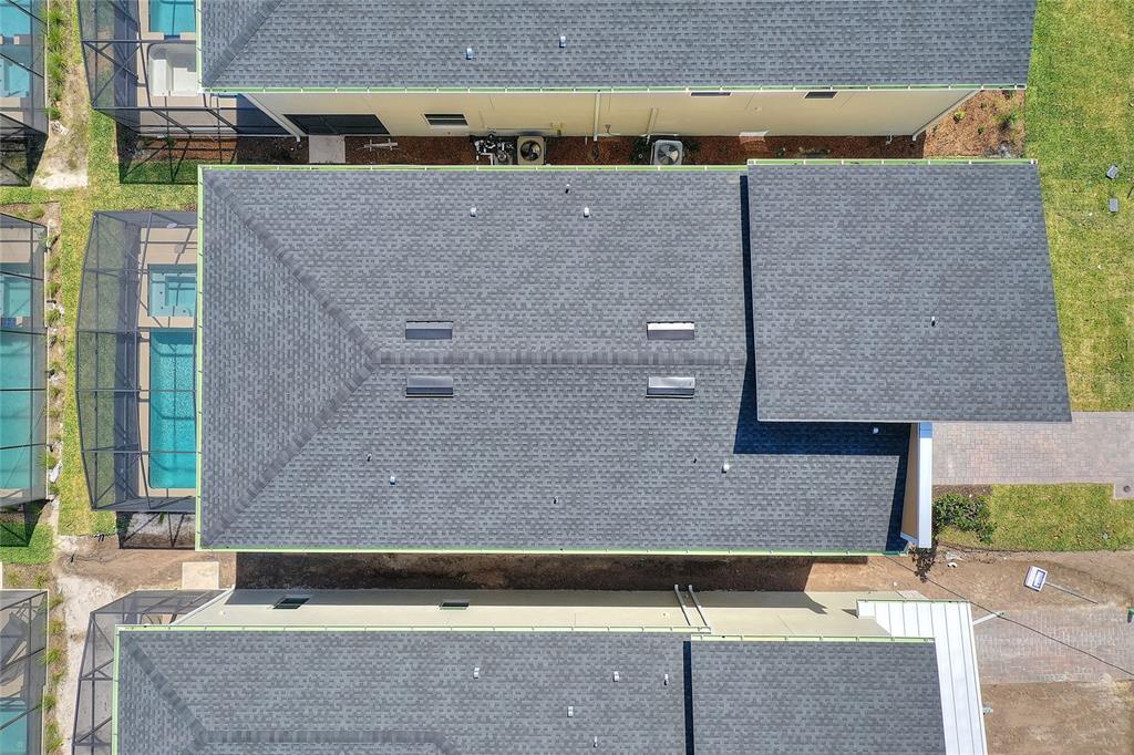 An aerial view shows the dark shingled roof of a house with a swimming pool enclosure — 4285 PROLOGUE WAY, KISSIMMEE, FL