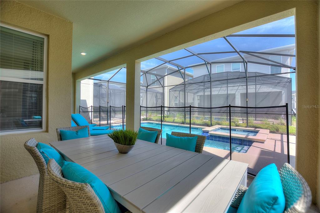 A covered patio features a dining set and a screened-in pool with a hot tub — 4285 PROLOGUE WAY, KISSIMMEE, FL