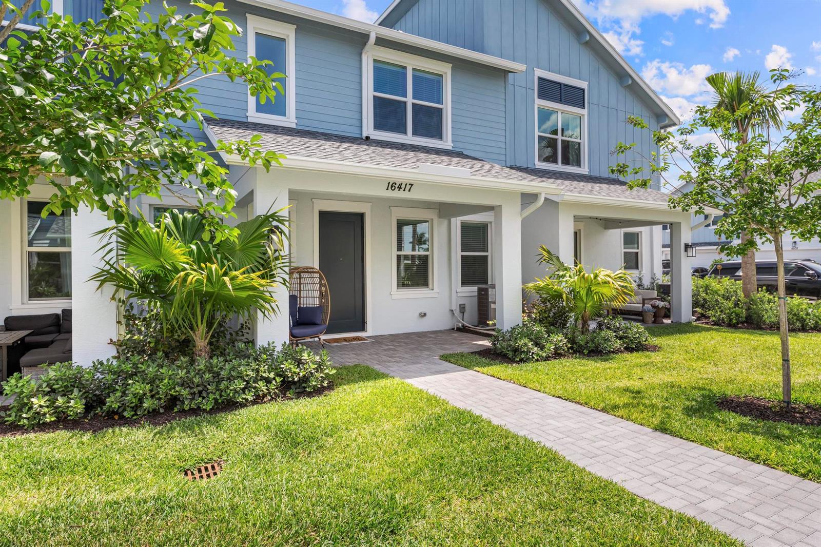 A blue two-story house features a covered front porch, a paved walkway, and landscaping — 16417 Mirabell Manor Lane, FL 33470, FL