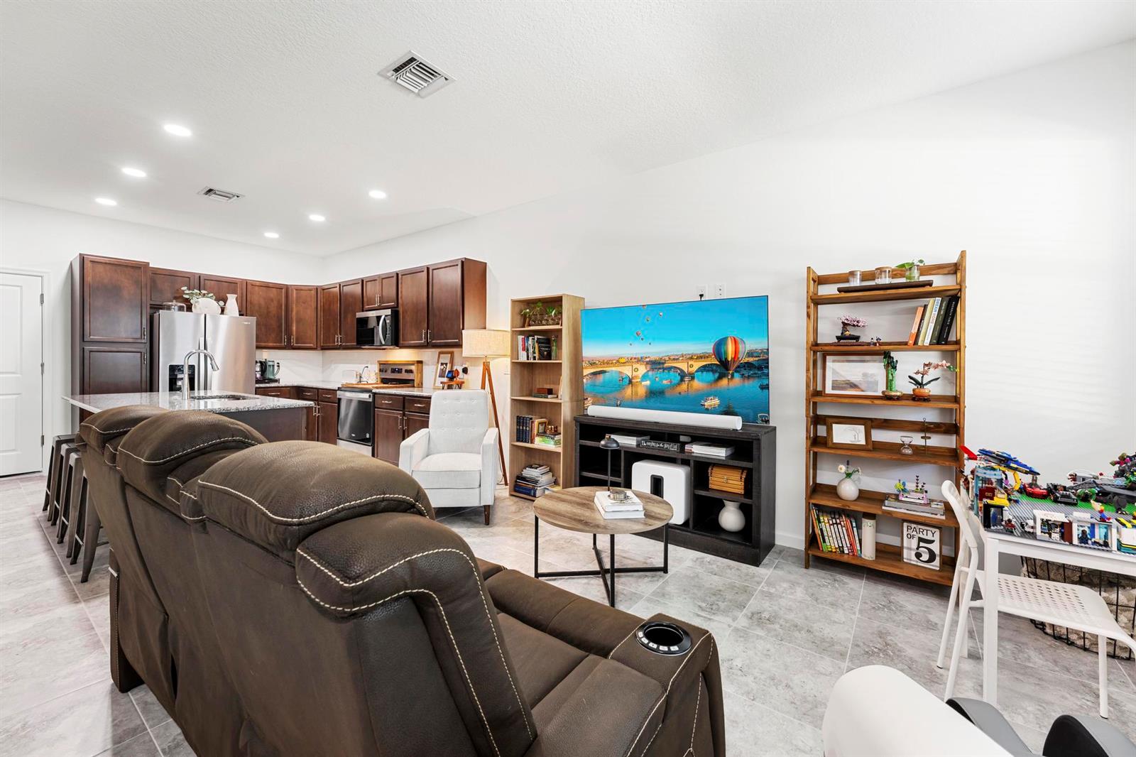 An open-concept living room and kitchen featuring dark wood cabinetry, tile flooring, and a sofa — 16417 Mirabell Manor Lane, FL 33470, FL