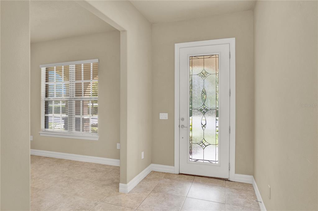 An entryway with beige walls, tile flooring, and a white door with decorative glass — 11322 LEMON LAKE BOULEVARD, ORLANDO, FL