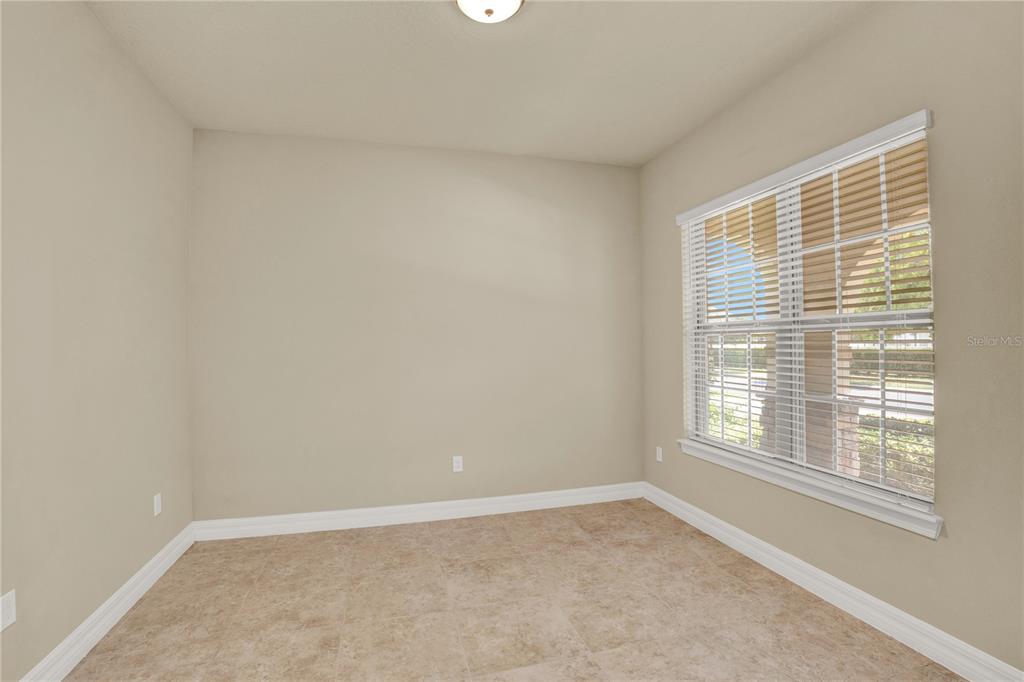 An empty room features beige walls, tile flooring, and a window with wooden blinds — 11322 LEMON LAKE BOULEVARD, ORLANDO, FL