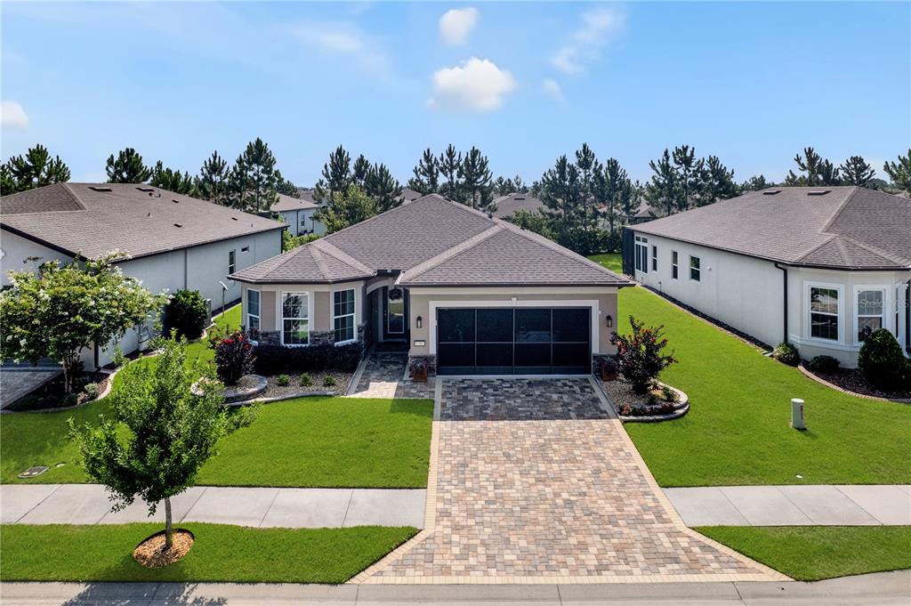 An aerial view of a single-story suburban house with a paved driveway and green lawn — 9381 SW 56TH LOOP, OCALA, FL