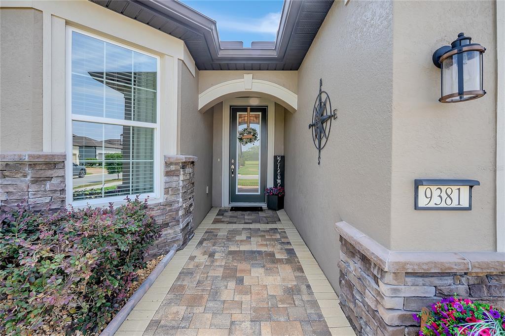 A paved walkway leads to the front entrance of a house with stone accents — 9381 SW 56TH LOOP, OCALA, FL