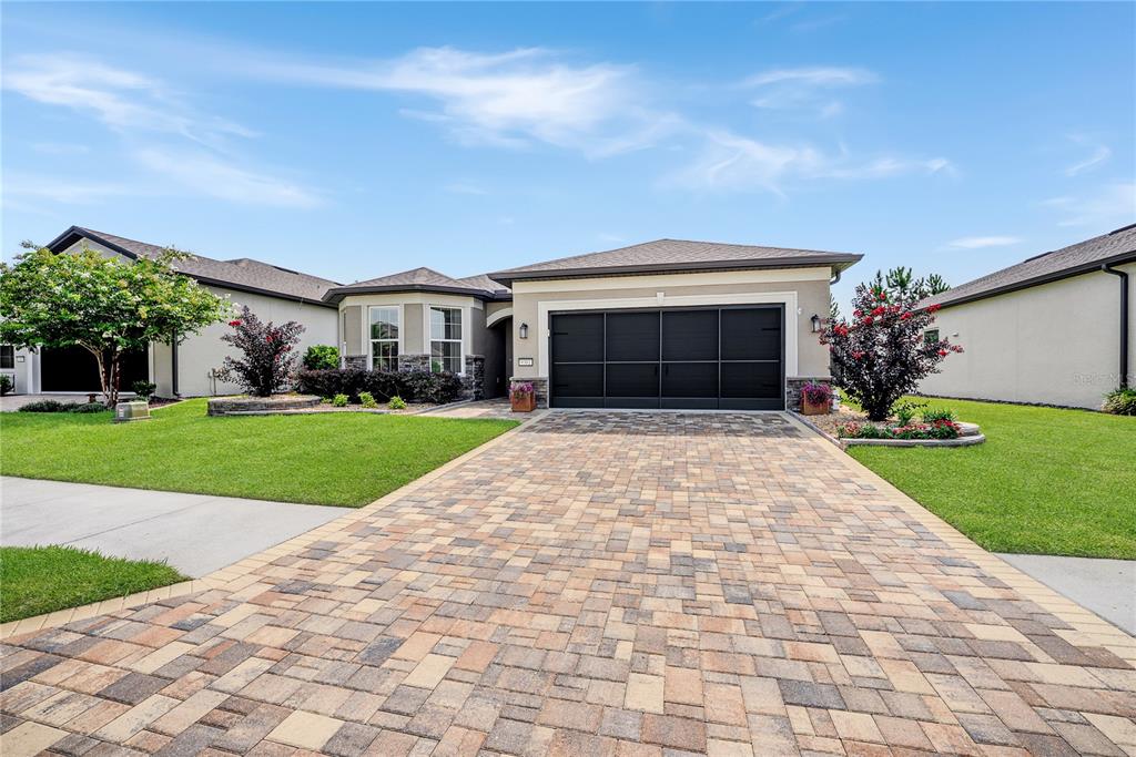 A single-story house with a paved driveway, a dark garage door, and a landscaped front yard — 9381 SW 56TH LOOP, OCALA, FL