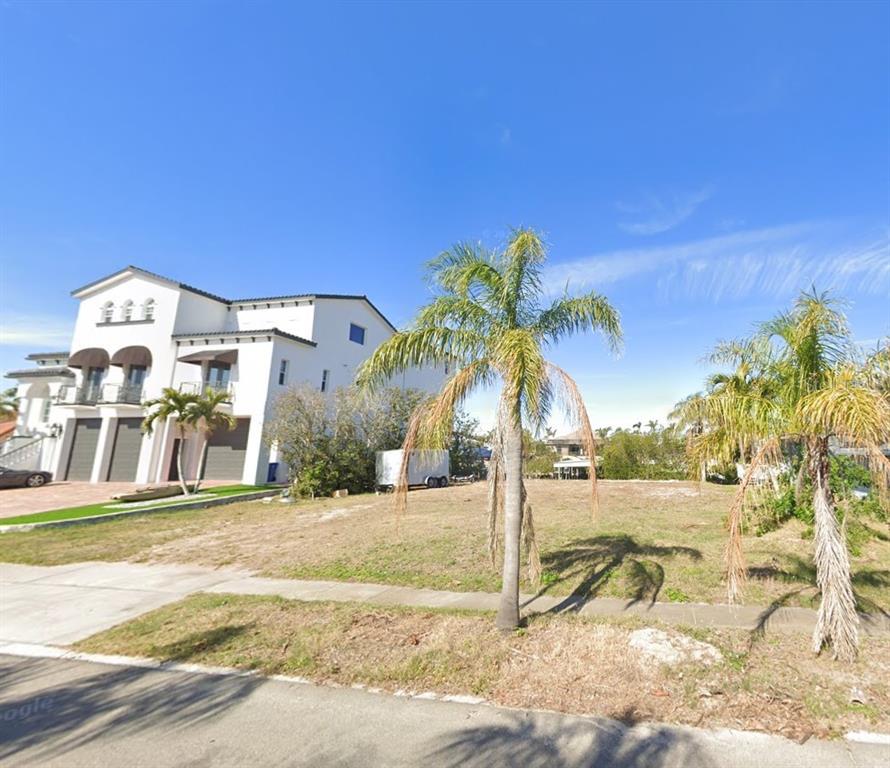 A vacant lot sits next to a large, multi-story white house with palm trees — 6508 BLACKFIN WAY, APOLLO BEACH, FL