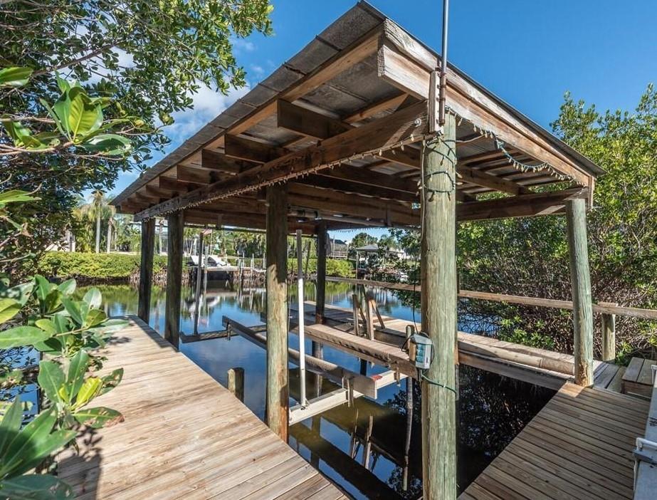 A wooden boat dock with a covered slip sits over a canal surrounded by mangroves — 6508 BLACKFIN WAY, APOLLO BEACH, FL