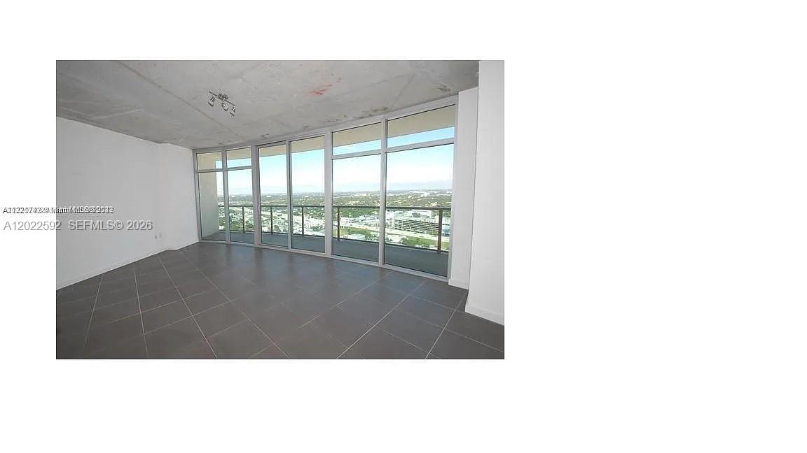 An empty room features large floor-to-ceiling windows, a concrete ceiling, and dark tiled flooring — 3301 NE 1st Ave # H2709, Miami FL 33137, MIAMI, FL