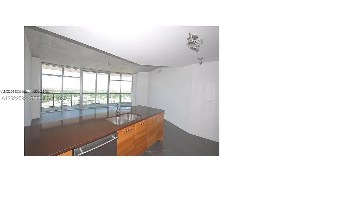 A modern kitchen features wood cabinets, dark countertops, and floor-to-ceiling windows with city views — 3301 NE 1st Ave # H2709, Miami FL 33137, MIAMI, FL