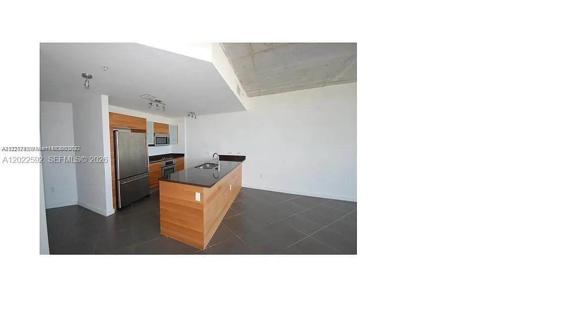 A modern kitchen features wood cabinets, a dark island countertop, and gray tile flooring — 3301 NE 1st Ave # H2709, Miami FL 33137, MIAMI, FL