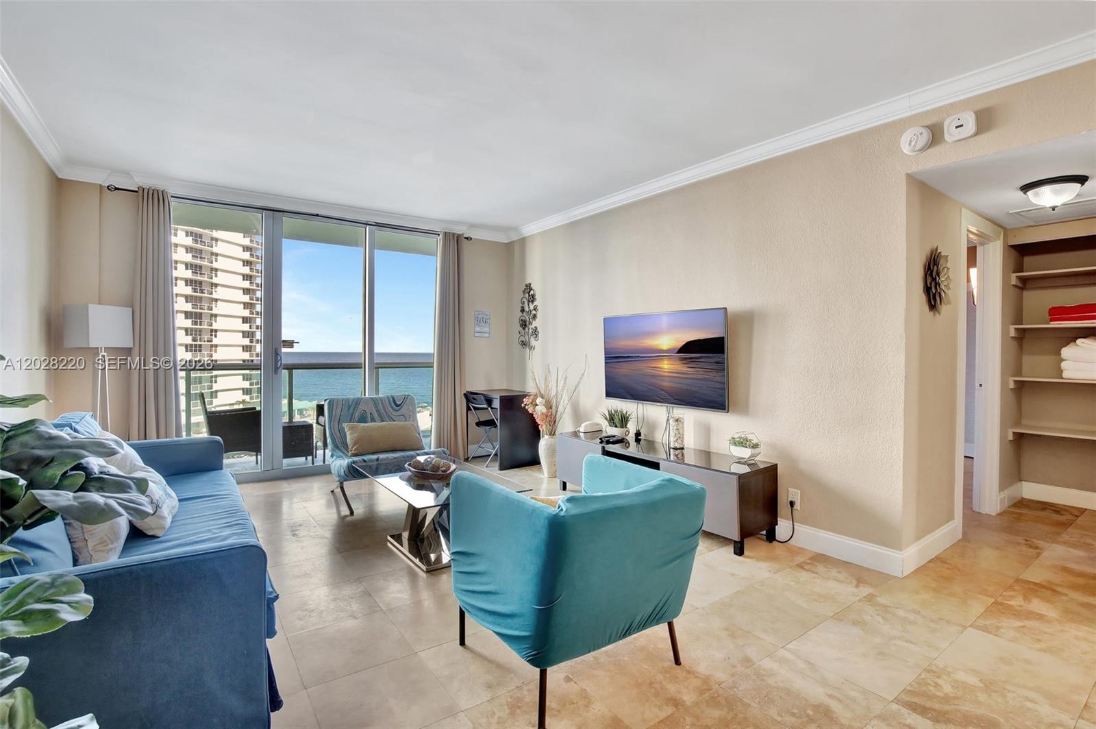 A living room features blue furniture, tile flooring, a wall-mounted television, and ocean views — 3801 S Ocean Dr # 6Z, Hollywood FL 33019, HOLLYWOOD, FL