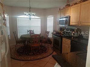 A kitchen with light wood cabinets and black countertops features an adjacent circular dining area — 11712 HATCHER CIRCLE, ORLANDO, FL