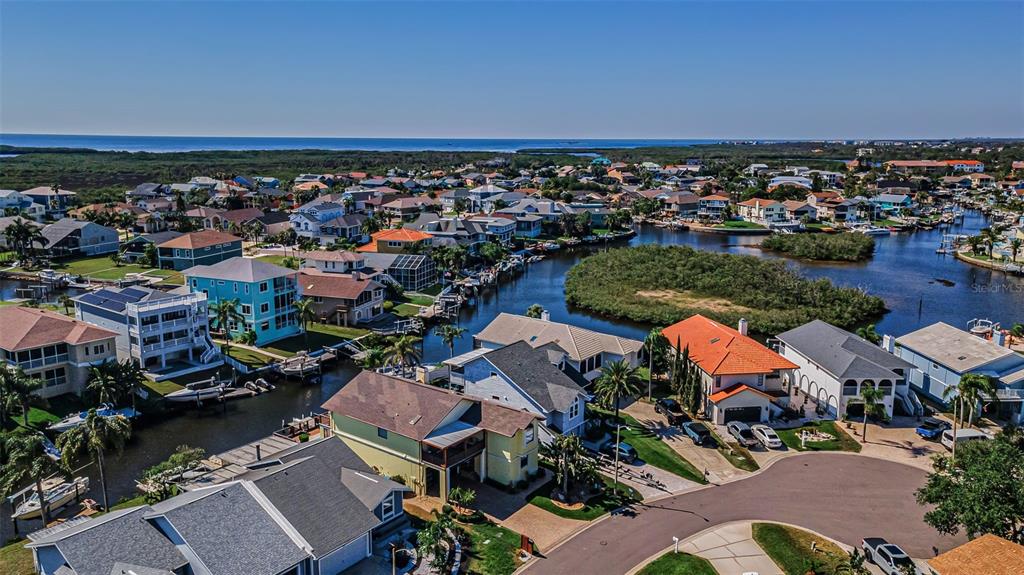 An aerial view shows waterfront houses with boat docks along a canal near the ocean — 6009 BAYWAY COURT, NEW PORT RICHEY, FL
