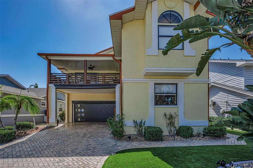A two-story yellow house with a paved driveway, a garage, and an upper-level balcony — 6009 BAYWAY COURT, NEW PORT RICHEY, FL