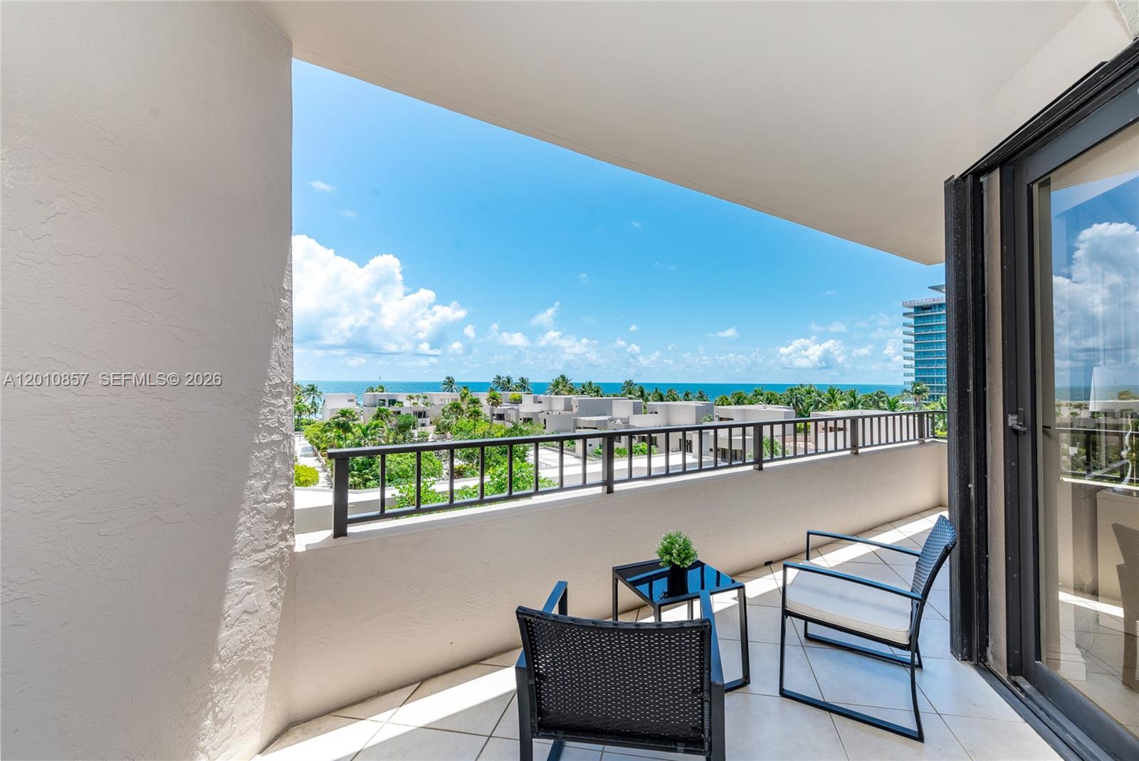 A balcony with two chairs and a small table overlooks a coastal landscape — 201 Crandon Blvd # 505, Key Biscayne FL 33149, KEY BISCAYNE, FL