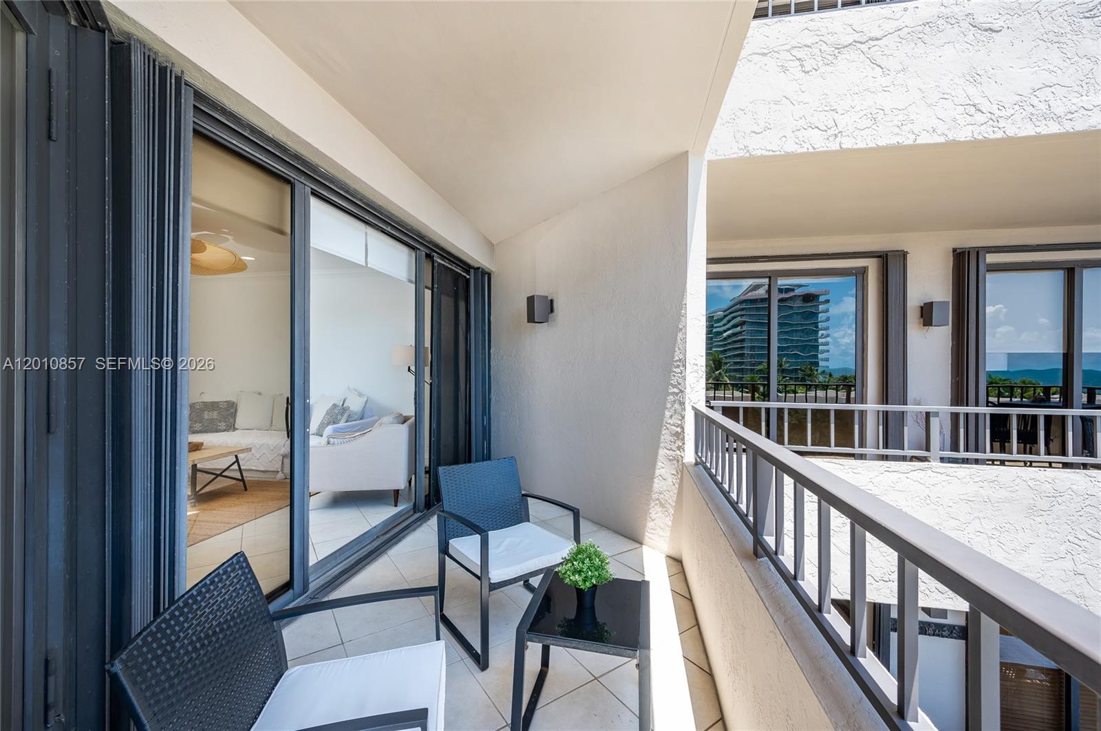 A balcony features two chairs, a small table, and sliding glass doors leading indoors — 201 Crandon Blvd # 505, Key Biscayne FL 33149, KEY BISCAYNE, FL