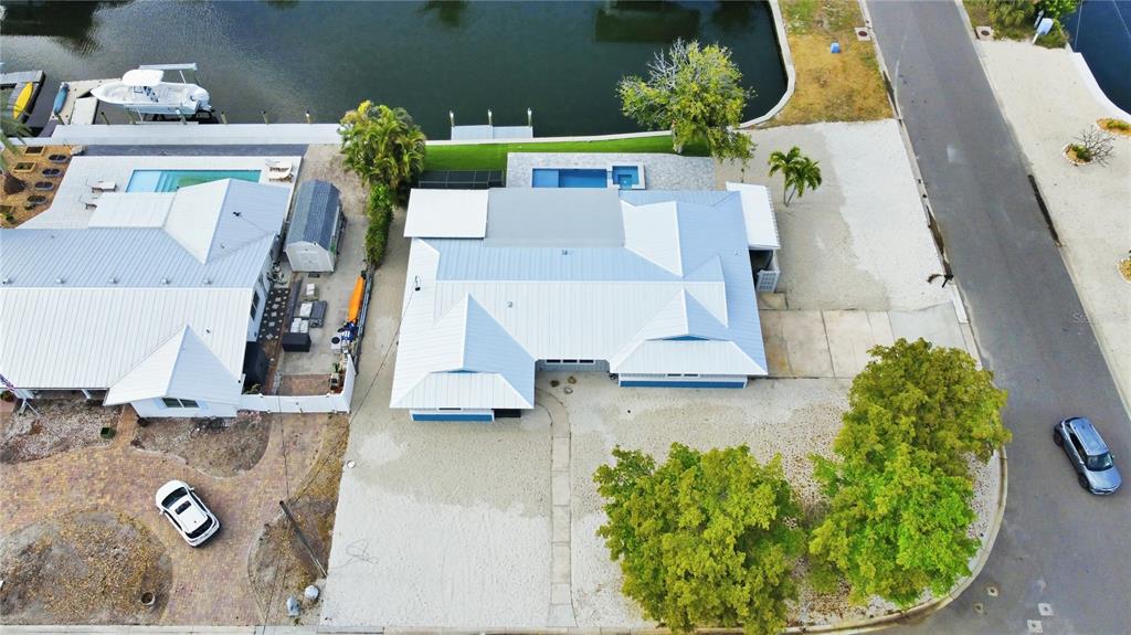 An aerial view shows a waterfront house with a metal roof, pool, and boat dock — 10304 KINGFISHER ROAD W, BRADENTON, FL