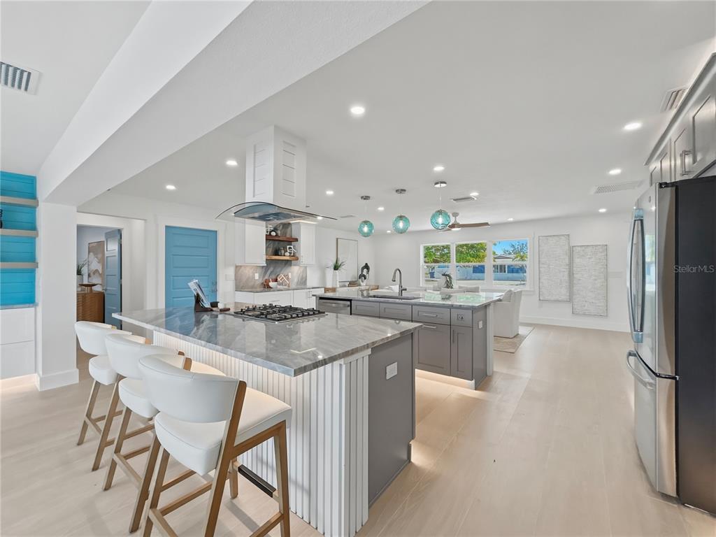 A modern kitchen features a large gray island with bar seating and white cabinetry — 10304 KINGFISHER ROAD W, BRADENTON, FL