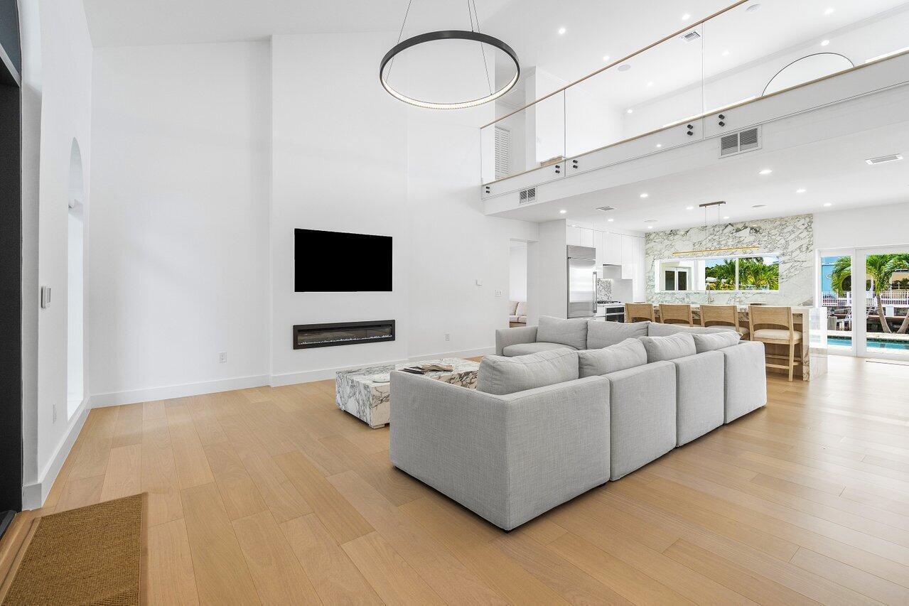 A modern living room features a large gray sectional sofa, fireplace, and high ceilings — 1366 SW 4th Court, Boca Raton FL 33432, BOCA RATON, FL