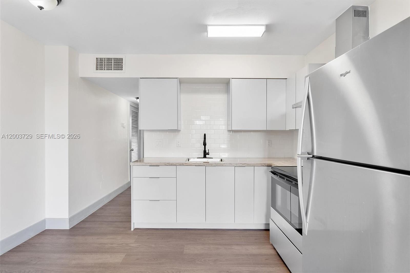 A bedroom features a bed with neutral bedding, two lamps, wall art, and a storage cabinet — 1715 N 16th Ave # 111, Hollywood FL 33020, HOLLYWOOD, FL