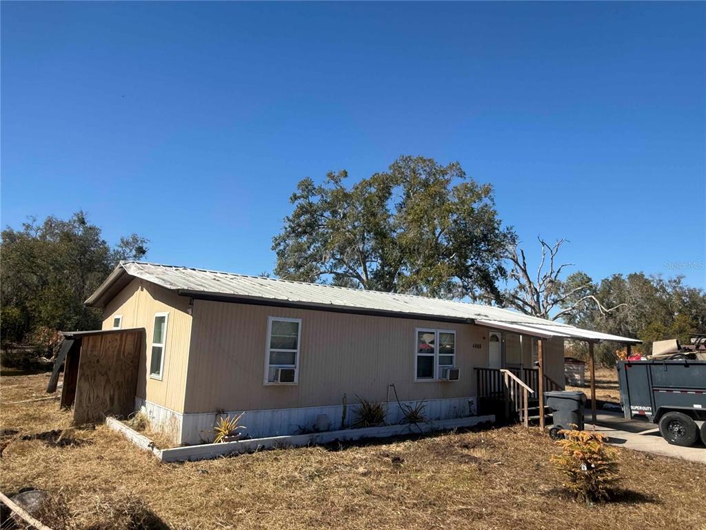 A single-story manufactured home with tan siding and a metal roof sits on a lot — 4008 PINE LANE, HAINES CITY, FL