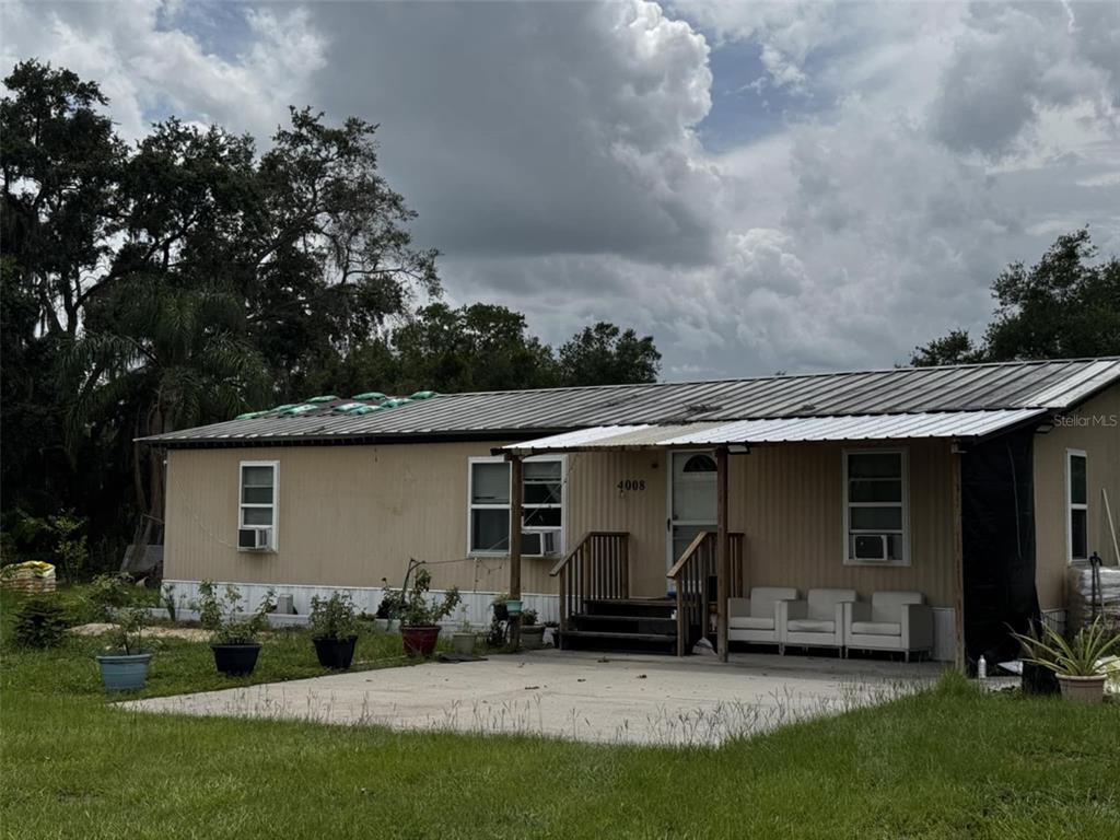 A single-story manufactured home with a metal roof and a concrete patio in the front — 4008 PINE LANE, HAINES CITY, FL