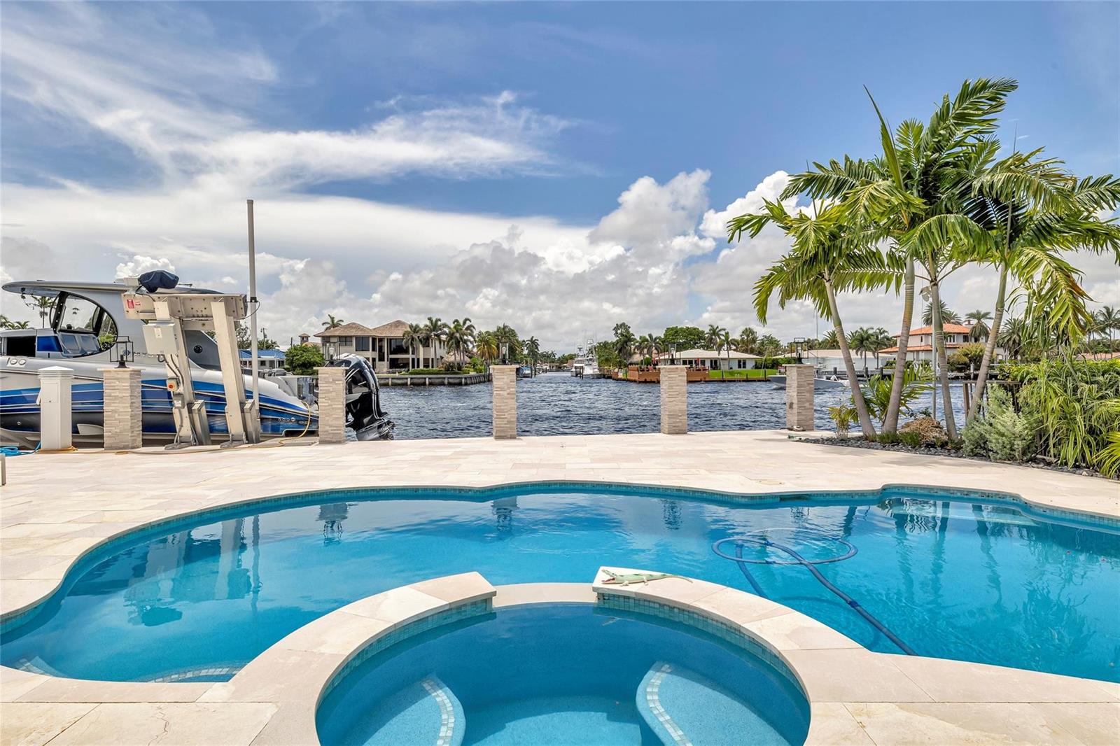 A swimming pool and hot tub overlook a canal with a boat lift and palm trees — 2005 N Riverside Drive, Pompano Beach FL 33062, POMPANO BEACH, FL