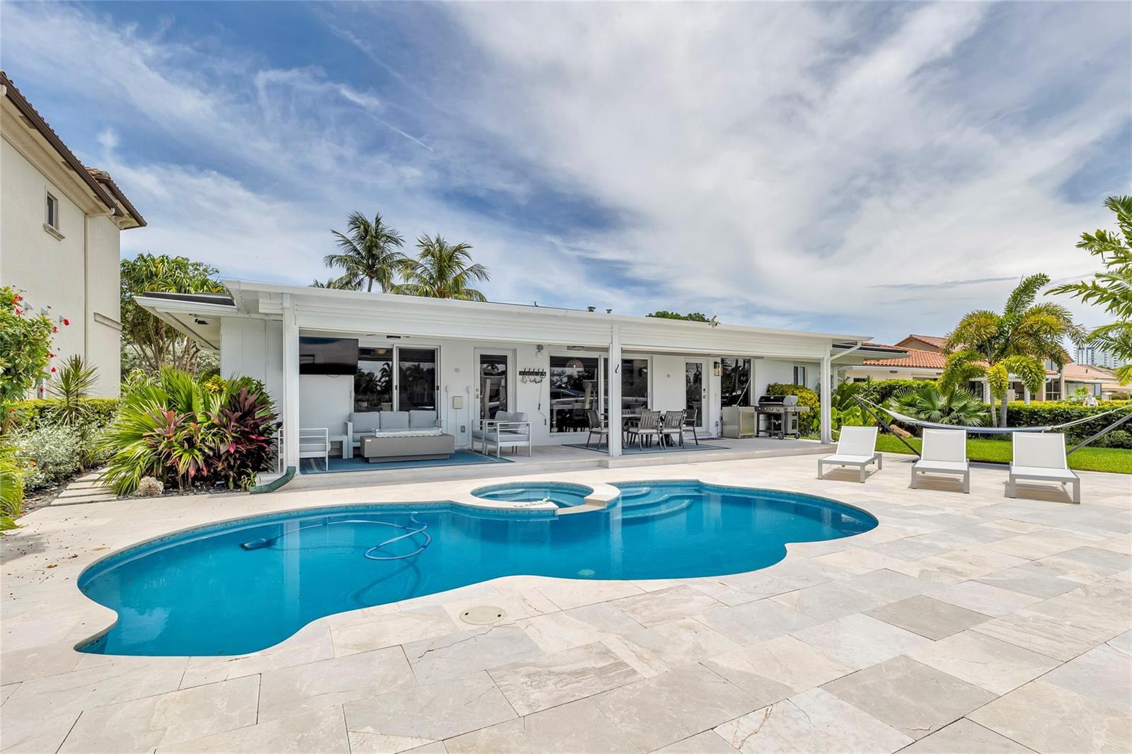 A backyard features a swimming pool, a covered patio with furniture, and lounge chairs — 2005 N Riverside Drive, Pompano Beach FL 33062, POMPANO BEACH, FL