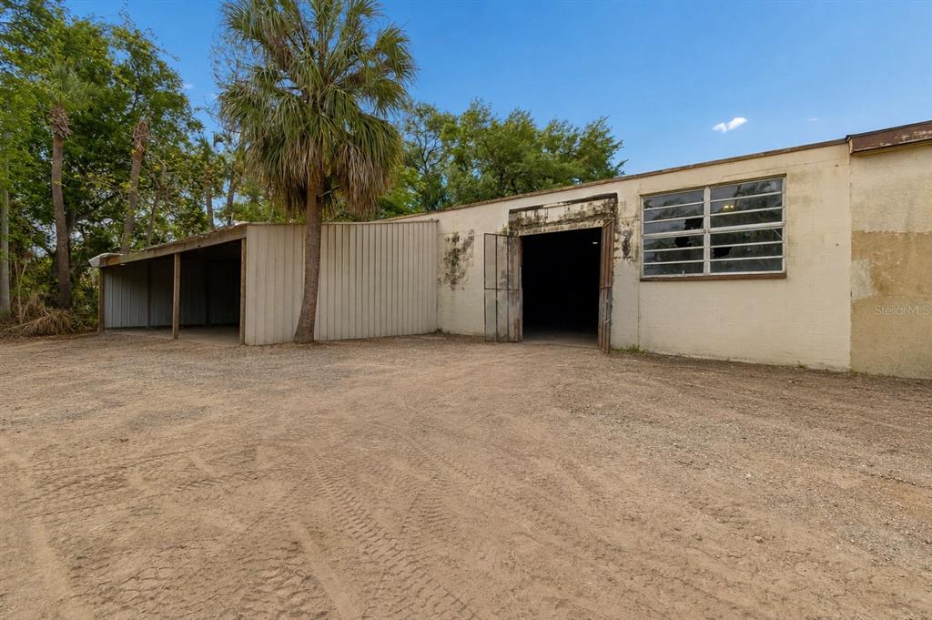An exterior view of a beige industrial building with a large open bay and carport — 4214 W VIRGINIA AVE UNIT 12, TAMPA, FL
