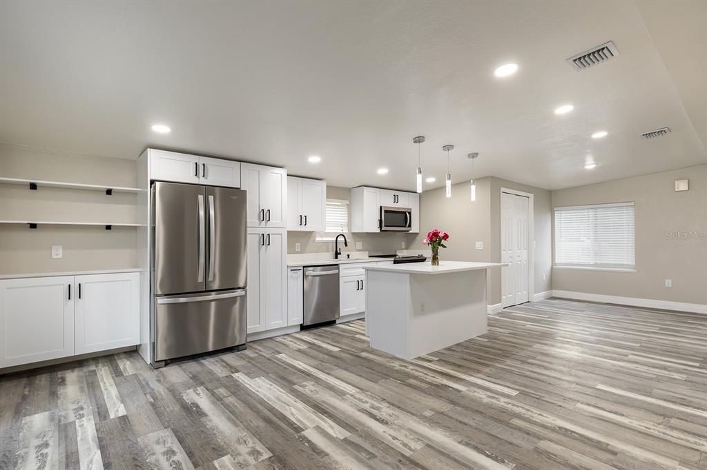 A modern kitchen features white cabinetry, stainless steel appliances, a center island, and wood-look flooring — 1007 SAN DOMINGO ROAD, ORLANDO, FL