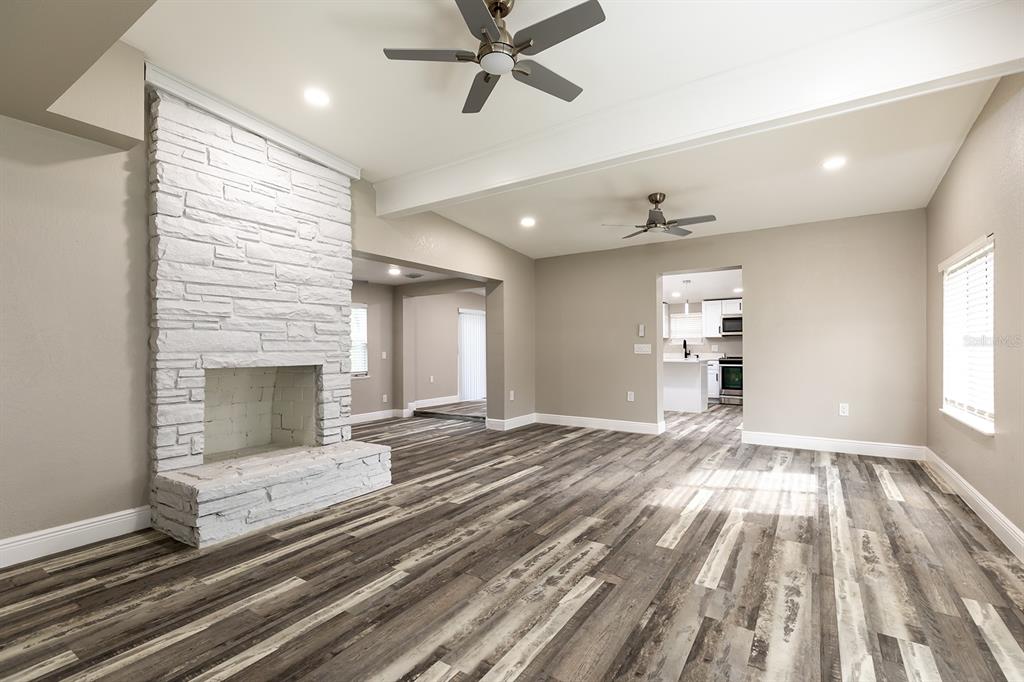 A living room features a white stone fireplace, wood-look flooring, and two ceiling fans — 1007 SAN DOMINGO ROAD, ORLANDO, FL