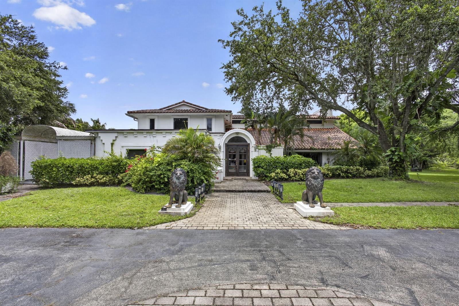 A white two-story house with a tiled roof features a brick walkway flanked by lion statues — 1030 Arabian Drive, Loxahatchee FL 33470, LOXAHATCHEE, FL
