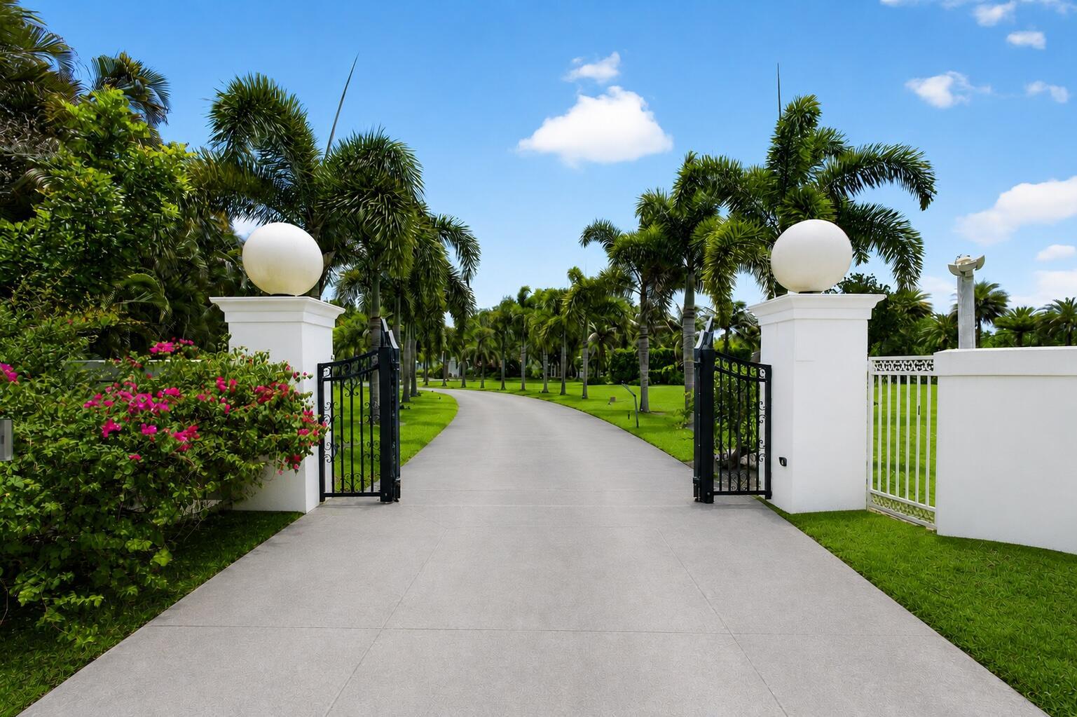 A paved driveway leads through an open gate flanked by white pillars and palm trees — 1030 Arabian Drive, Loxahatchee FL 33470, LOXAHATCHEE, FL