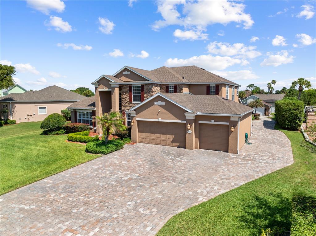 A two-story house with a stone facade, brown stucco, and a paved driveway — 1620 MARINA LAKE DR, KISSIMMEE, FL