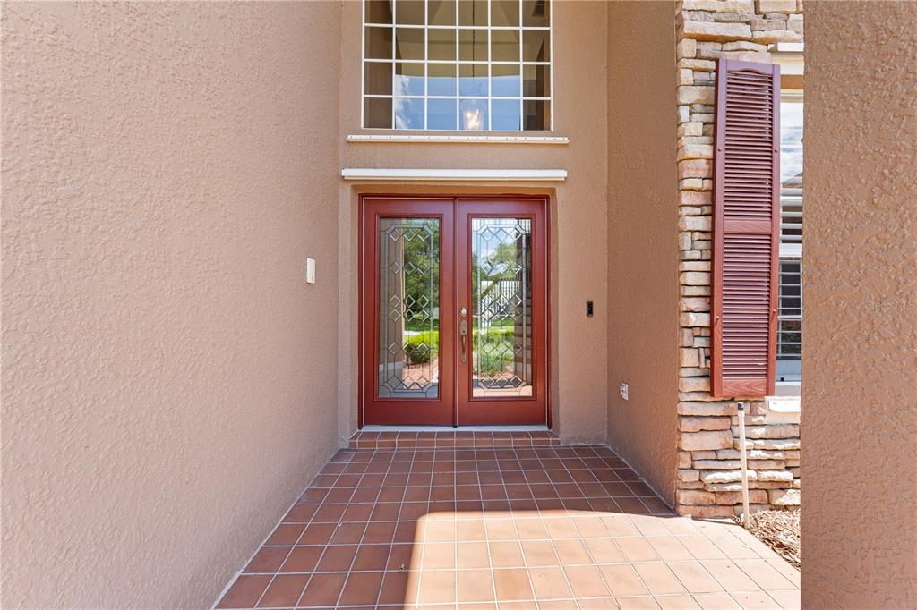A front entryway features double glass-paneled doors, a tiled porch, and stone-accented exterior walls — 1620 MARINA LAKE DR, KISSIMMEE, FL