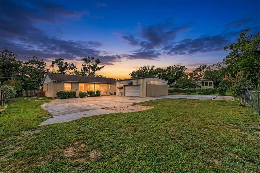 A house and a detached garage sit on a large grassy lot at sunset — 2216 PINECREST DRIVE, LUTZ, FL