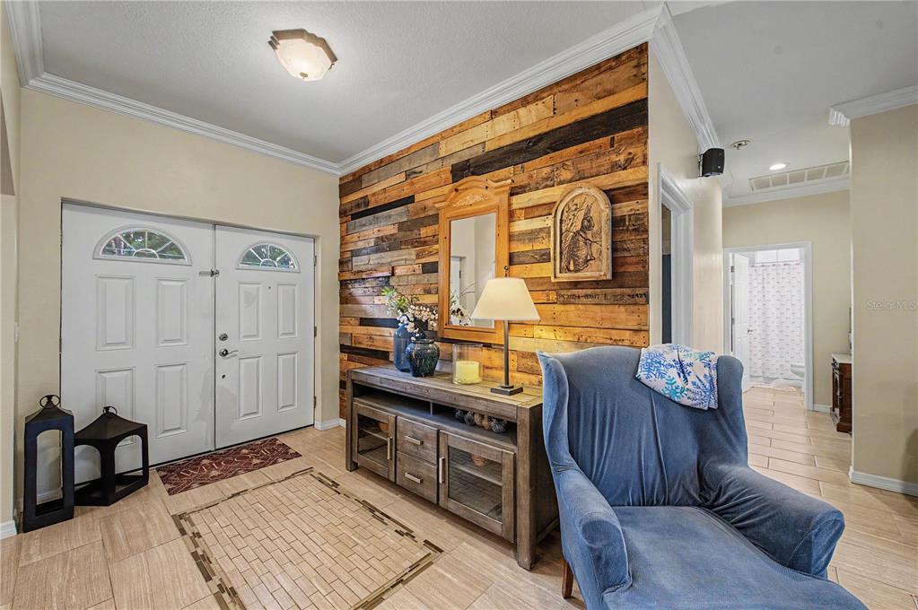 An entryway features a wood-plank accent wall, a console table, and a blue armchair — 2216 PINECREST DRIVE, LUTZ, FL