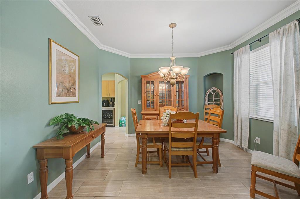 A dining room with sage green walls, a wooden table set, and tile flooring — 2216 PINECREST DRIVE, LUTZ, FL