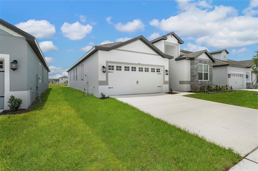 A white single-story house with a two-car garage and stone accents on the front facade — 3360 CHINOTTO DRIVE, LAKE ALFRED, FL