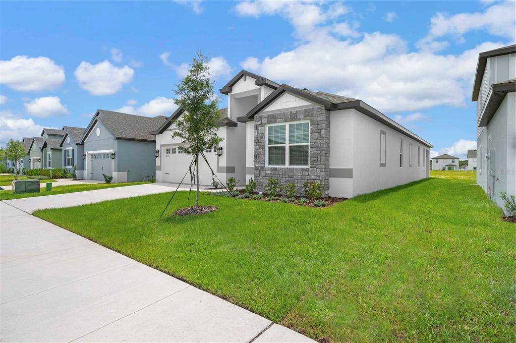 A single-story house with a white stucco exterior, stone accents, and a two-car garage — 3360 CHINOTTO DRIVE, LAKE ALFRED, FL