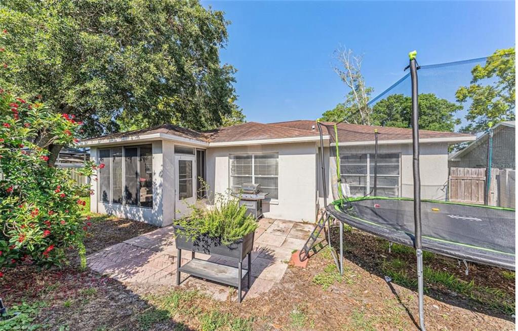 The backyard features a paved patio, a raised planter, and a trampoline near the house — 7330 FAIRWOOD AVENUE, NEW PORT RICHEY, FL