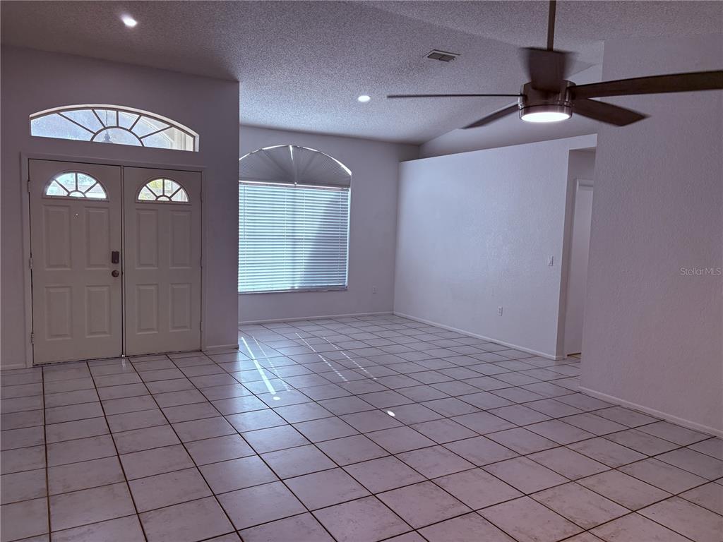 An empty room features white tile flooring, a ceiling fan, and arched windows — 7330 FAIRWOOD AVENUE, NEW PORT RICHEY, FL