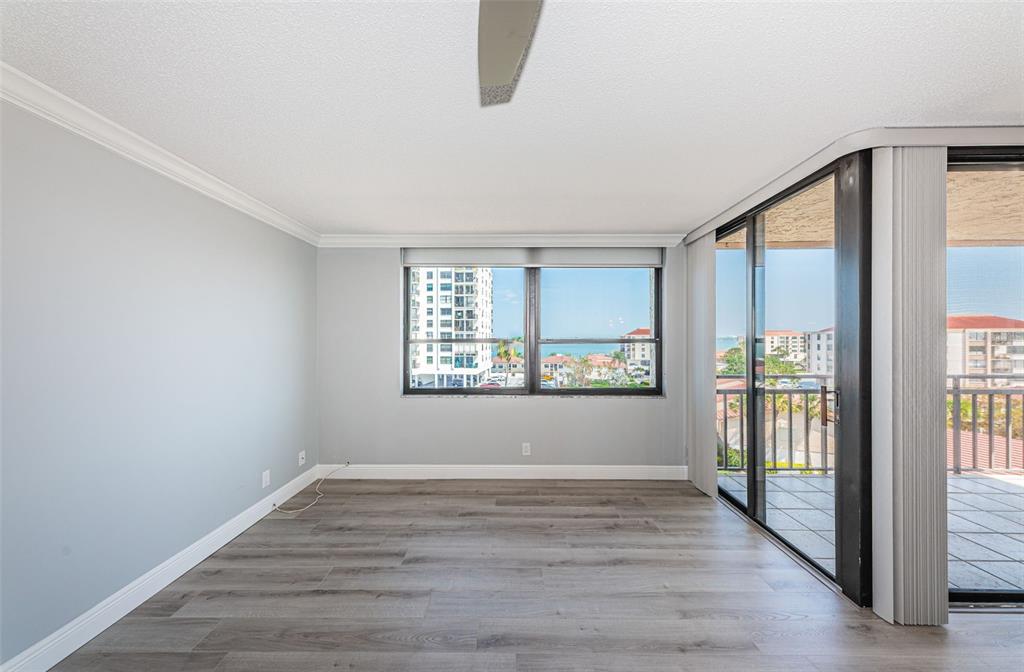 An empty room with gray walls, wood-look flooring, a ceiling fan, and a balcony view — 6279 SUN BOULEVARD UNIT 604, ST PETERSBURG, FL