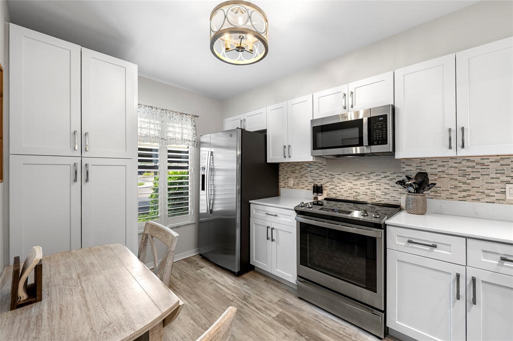 A kitchen with white cabinets, stainless steel appliances, and a small dining table — 6015 27TH STREET W UNIT 1C, BRADENTON, FL