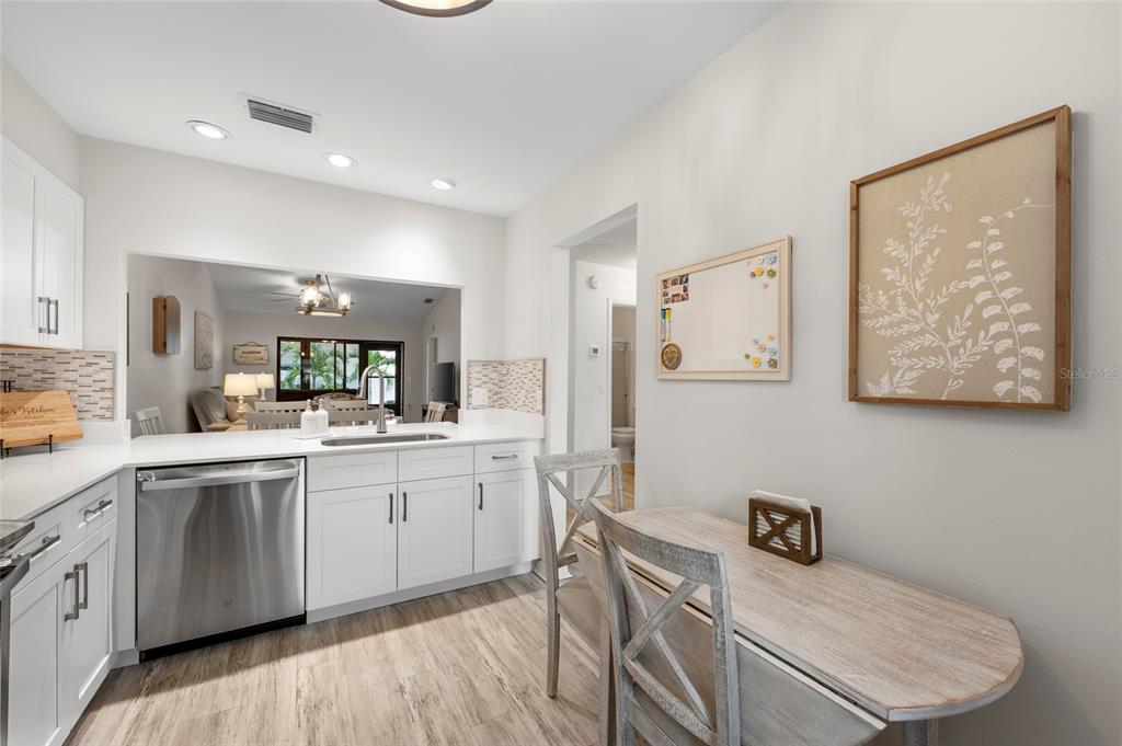 A kitchen with white cabinets, stainless steel appliances, and a small dining table with chairs — 6015 27TH STREET W UNIT 1C, BRADENTON, FL
