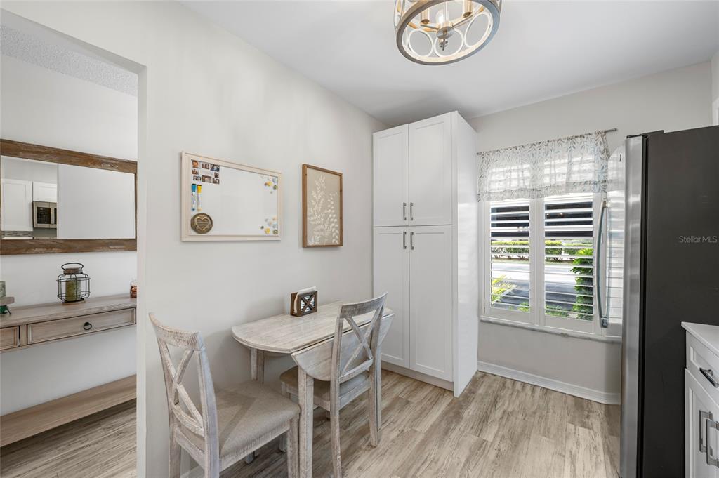 A dining nook features a small table with two chairs, white cabinetry, and wood-look flooring — 6015 27TH STREET W UNIT 1C, BRADENTON, FL