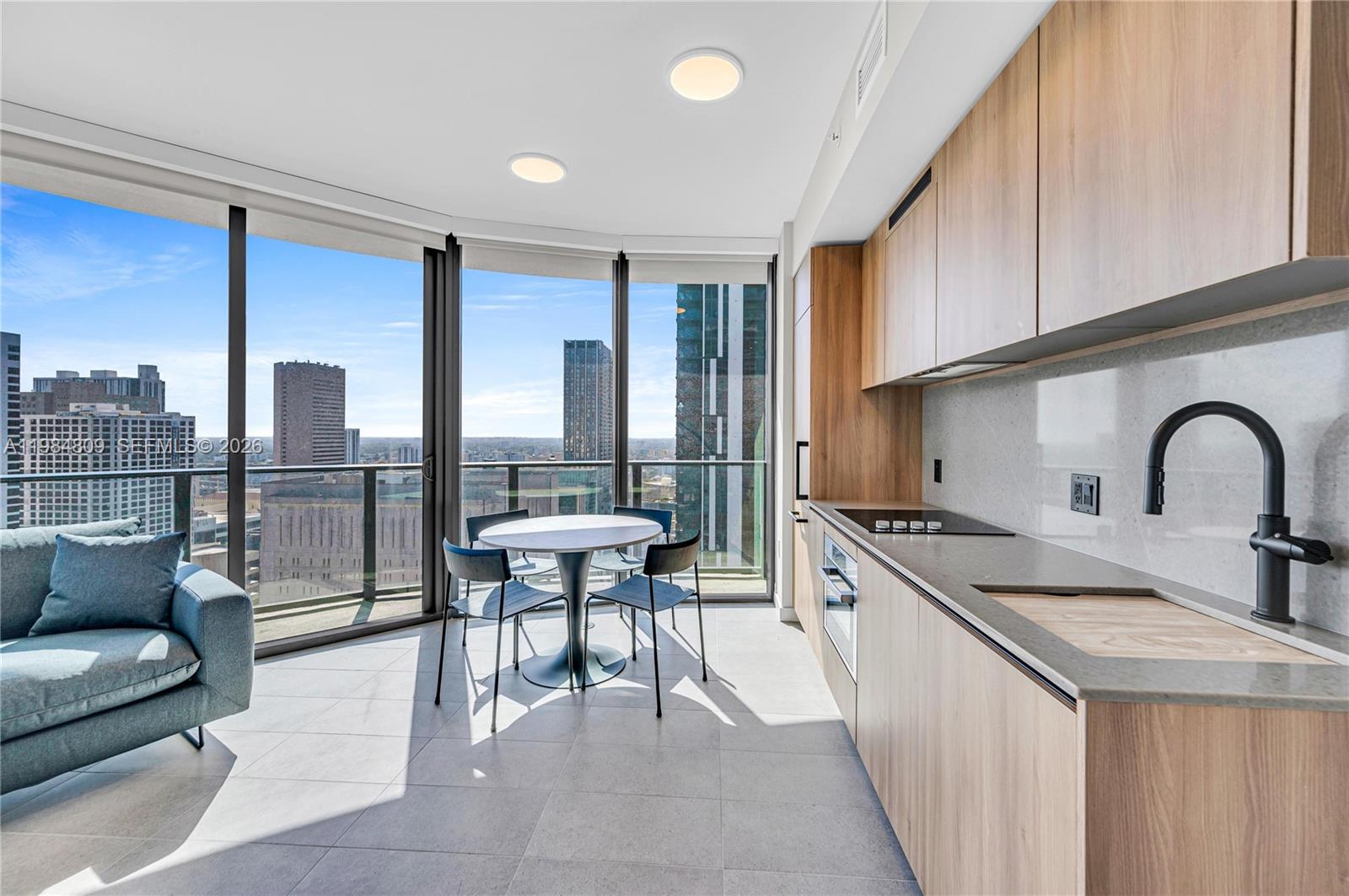 A modern kitchen and dining area features light wood cabinetry, a city view, and floor-to-ceiling windows — 121 NE 5th St # 3005, Miami FL 33130, MIAMI, FL