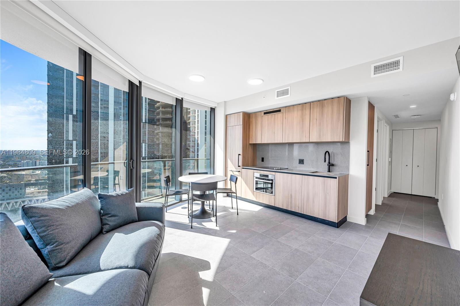 A modern studio apartment features a kitchenette, a dining area, and floor-to-ceiling windows — 121 NE 5th St # 3005, Miami FL 33130, MIAMI, FL