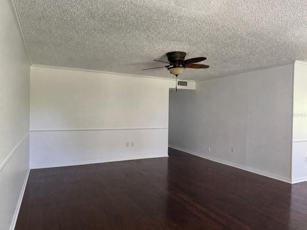 An empty room with dark wood flooring, white walls with chair rail, and a ceiling fan — 350 79TH AVE N UNIT 102, ST PETERSBURG, FL